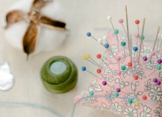 Jak uszyć proste poszewki na poduszki bez maszyny do szycia Poduszka z kolorowymi szpilkami, nicią i watą na stole w pracowni DIY