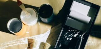 Ozdobne tace i patery DIY, które uporządkują drobiazgi Pędzle, wałki i puszki farby rozłożone na papierze z góry