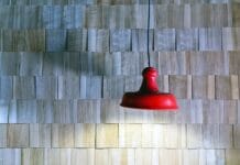 Jak zrobić panel ścienny z listewek DIY i wizualnie powiększyć wnętrze Czerwona lampa wisząca na tle drewnianej ściany z listewek