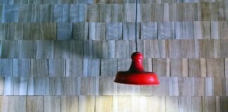 Czerwona lampa wisząca na tle drewnianej ściany z listewek