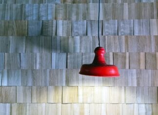 Czerwona lampa wisząca na tle drewnianej ściany z listewek